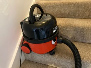 A Henry vacuum balancing on a stair tread.